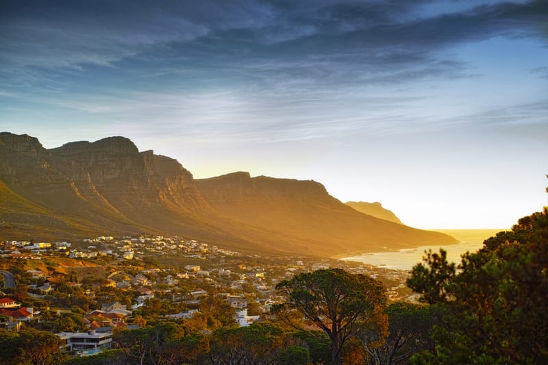 Die Felsgrate der Twelve Apostles leuchten golden über den Häusern von Camps Bay