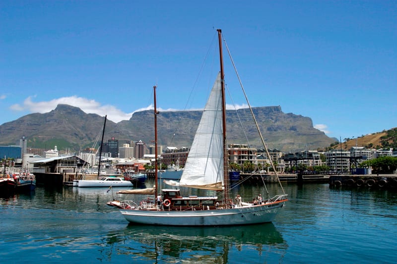 Ein Segelboot im Hafenbecken der V&A Waterfront, dahinter der Tafelberg